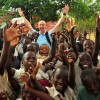U.S. Air Force Senior Airman Daniel McKittrick, a public affairs broadcaster, assigned to Combined Task Force - Horn of Africa (CJTF-HOA), celebrates with children before a water project dedication ceremony in Magu, Tanzania, Jan. 21, 2008. The Magu water project provides clean drinking water to thousands of villagers in the Magu region of Tanzania and is a example of how CJTF-HOA develops and nurtures partnerships to promote regional cooperation and create an environment for development (U.S. Air Force photo by Staff Sgt. Joseph L. Swafford Jr./Released)